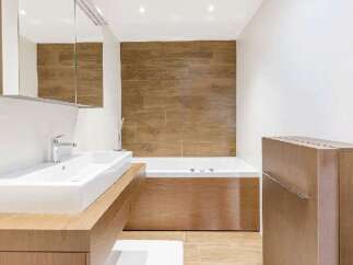 This modern bathroom features a sleek design with a wooden accent wall and cabinetry, creating a warm and inviting atmosphere.