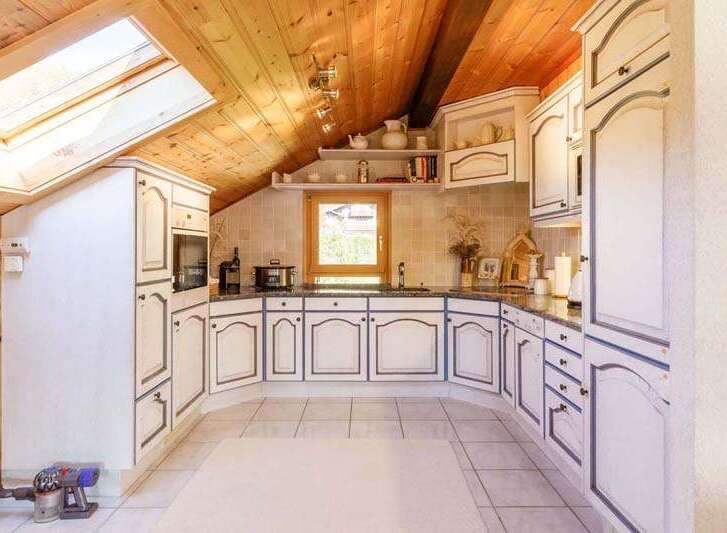 This charming kitchen boasts a unique design with its sloped ceiling and skylight, creating a bright and airy atmosphere.