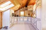 This charming kitchen boasts a unique design with its sloped ceiling and skylight, creating a bright and airy atmosphere.