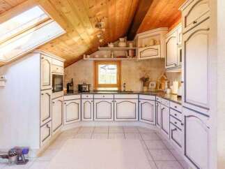 This charming kitchen boasts a unique design with its sloped ceiling and skylight, creating a bright and airy atmosphere.