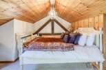 Experience rustic charm in this cozy bedroom, featuring a stunning wooden ceiling and exposed beams.