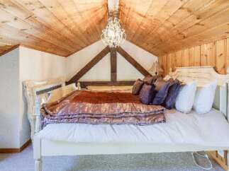 Experience rustic charm in this cozy bedroom, featuring a stunning wooden ceiling and exposed beams.