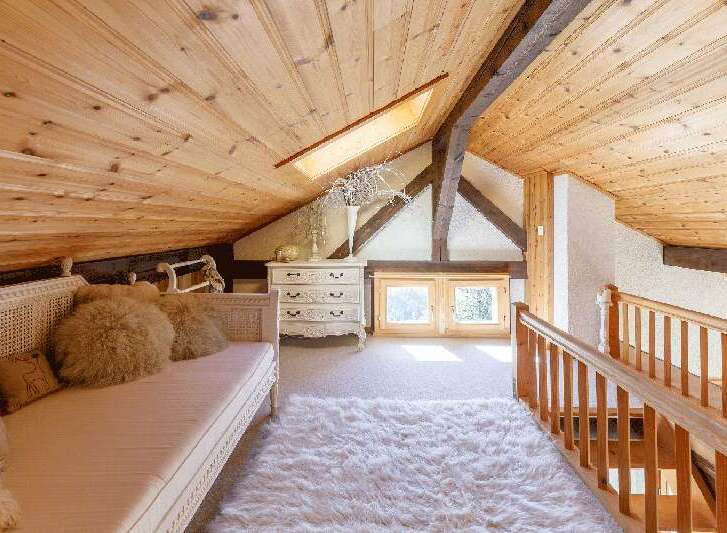 Discover the charm of this cozy attic space, featuring a warm wooden ceiling and a plush, inviting rug.