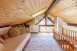 Discover the charm of this cozy attic space, featuring a warm wooden ceiling and a plush, inviting rug.