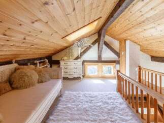 Discover the charm of this cozy attic space, featuring a warm wooden ceiling and a plush, inviting rug.