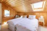 Cozy bedroom with wooden walls and ceiling, featuring two comfortable beds with white linens.