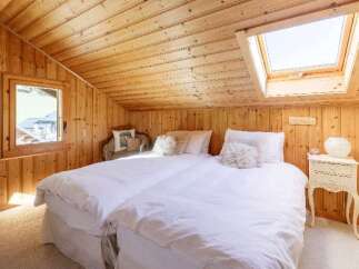 Cozy bedroom with wooden walls and ceiling, featuring two comfortable beds with white linens.