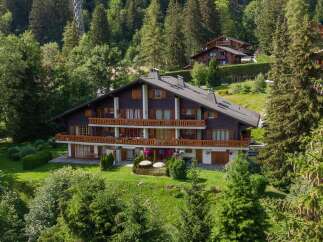 Nestled in a lush, green landscape, this stunning property boasts a classic chalet design with multiple levels and balconies.