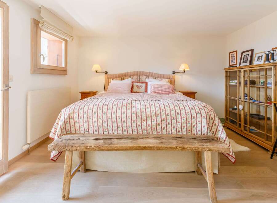 This charming bedroom features a rustic wooden bench at the foot of the bed, adding a touch of warmth and character.
