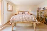 This charming bedroom features a rustic wooden bench at the foot of the bed, adding a touch of warmth and character.