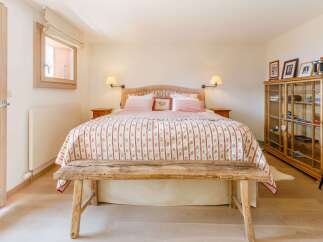 This charming bedroom features a rustic wooden bench at the foot of the bed, adding a touch of warmth and character.