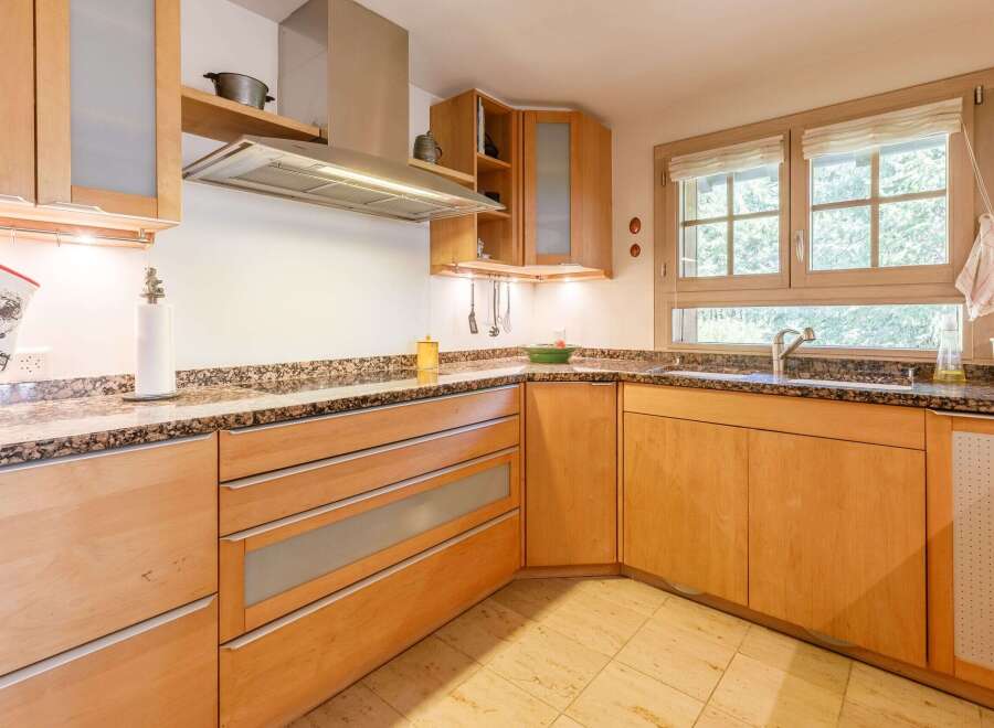 This beautiful kitchen features custom wooden cabinetry and granite countertops, creating a warm and inviting atmosphere.