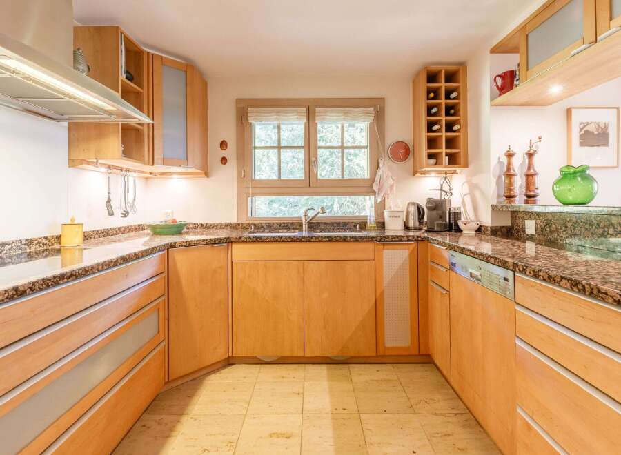 This stunning kitchen boasts custom wooden cabinetry and granite countertops, creating a warm and inviting atmosphere.