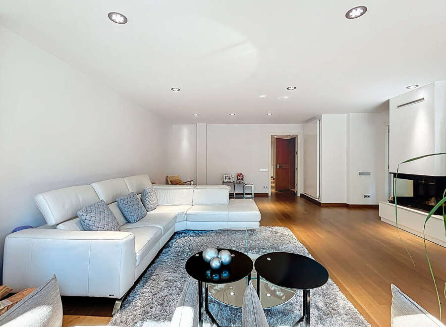 Stunning living room with a modern white leather sectional sofa, complemented by a plush gray rug and sleek black coffee tables.