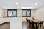 Modern kitchen with sleek white cabinetry and stunning mountain views from large windows.