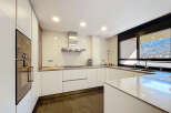Modern kitchen with sleek white cabinets and integrated appliances.