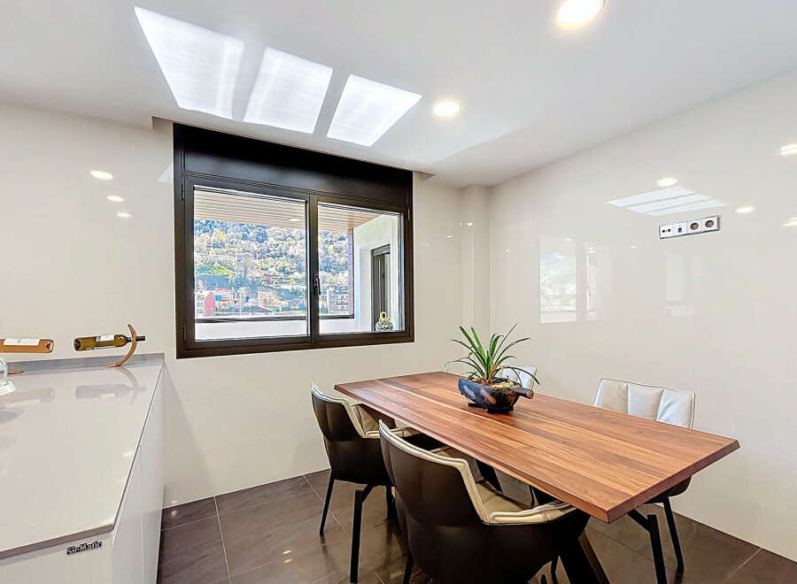 Modern kitchen with sleek countertops and a wooden dining table.