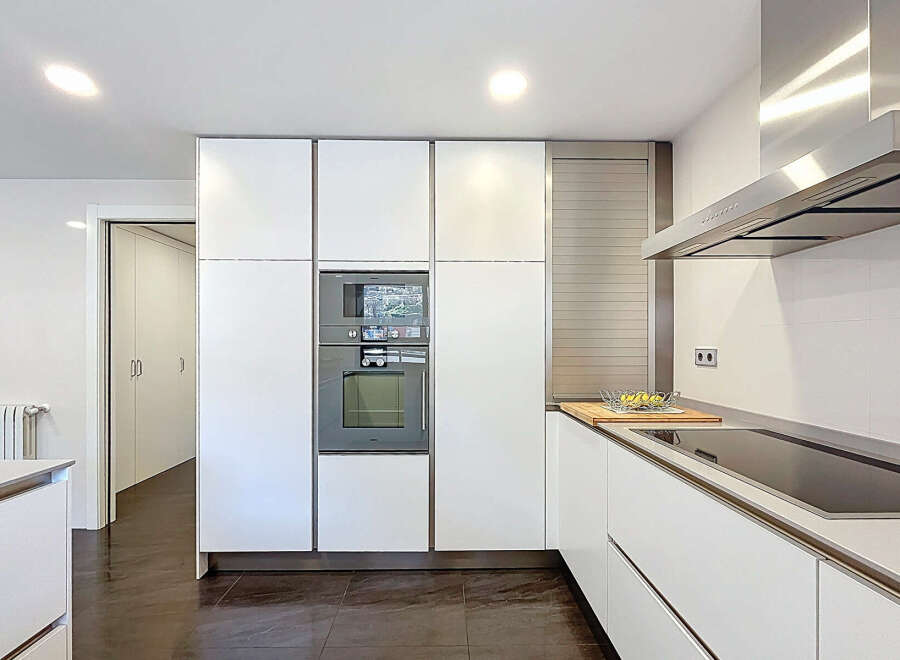 Modern kitchen with sleek white cabinets and integrated appliances.