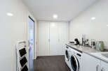 This stunning property boasts a modern laundry room with sleek white cabinetry and high-end appliances.