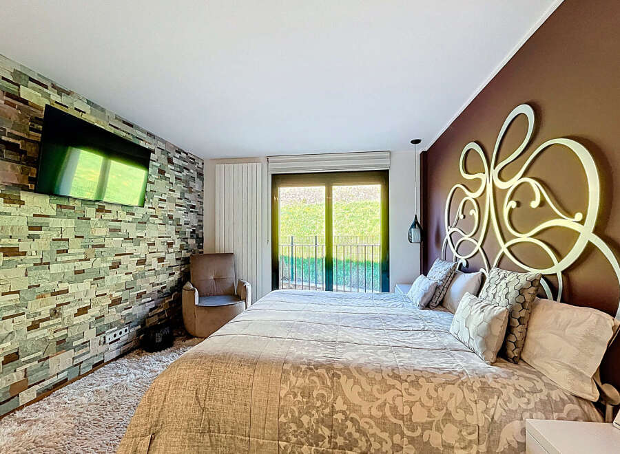 Luxurious bedroom with a stone feature wall, large bed, and modern decor.