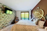Luxurious bedroom with a stone feature wall, large bed, and modern decor.