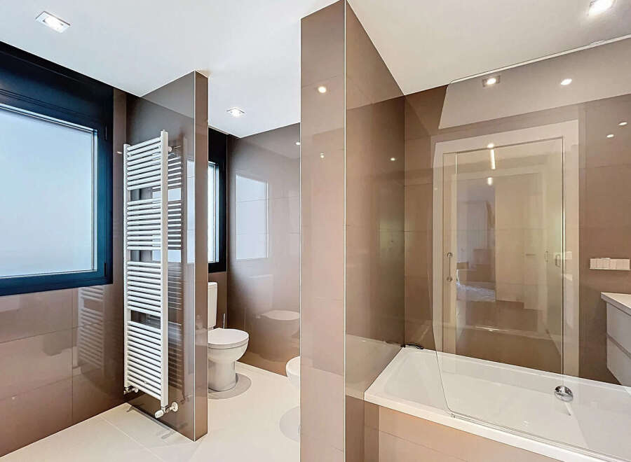Modern bathroom with a sleek design, featuring a glass shower enclosure, a built-in bathtub, and a heated towel rack.
