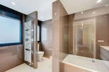 Modern bathroom with a sleek design, featuring a glass shower enclosure, a built-in bathtub, and a heated towel rack.