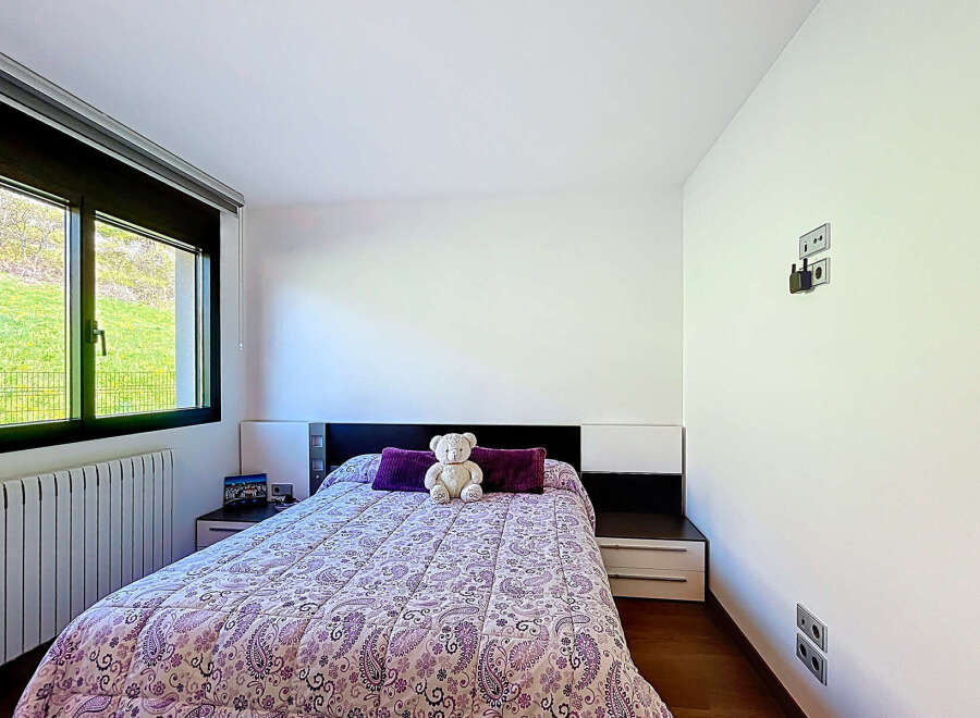Cozy bedroom with a double bed, featuring a purple and white paisley patterned comforter and plush pillows.