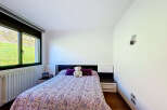 Cozy bedroom with a double bed, featuring a purple and white paisley patterned comforter and plush pillows.