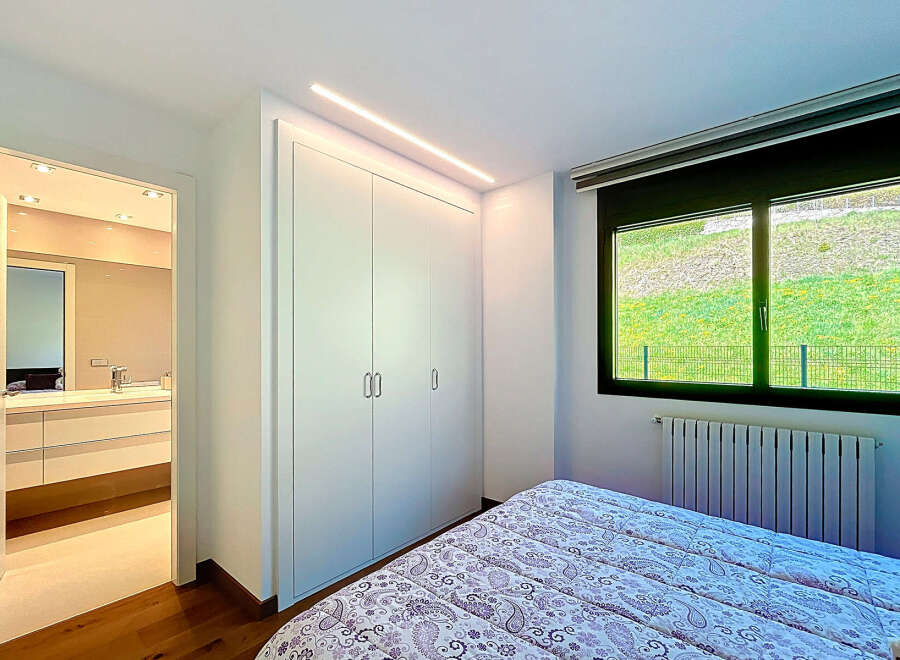 This stunning bedroom boasts built-in wardrobes and a view of a lush green landscape.
