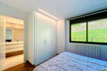 This stunning bedroom boasts built-in wardrobes and a view of a lush green landscape.