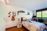 Cozy bedroom with built-in desk and window overlooking a lush green landscape.