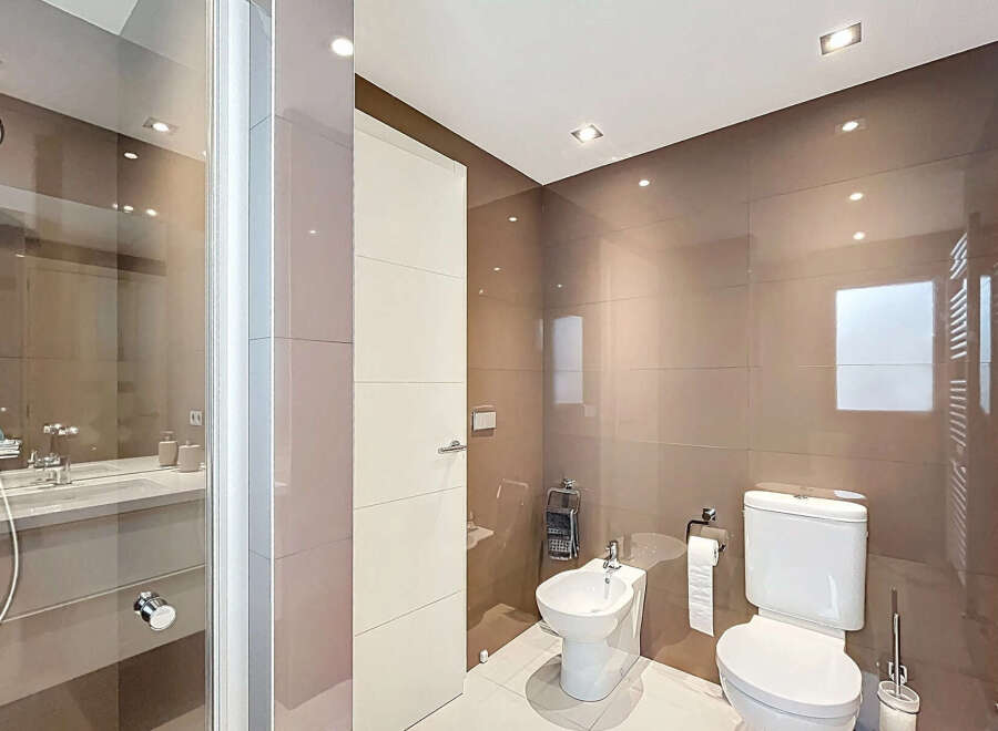 Modern bathroom with a walk-in shower, toilet, and bidet.