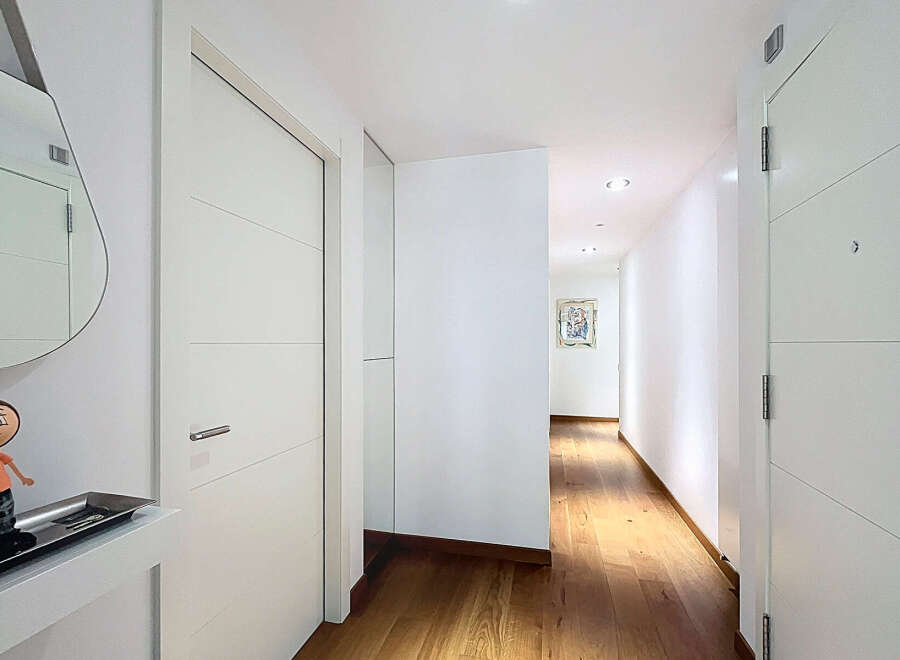 This stunning hallway boasts sleek, modern white doors and hardwood floors, creating an elegant and sophisticated atmosphere.