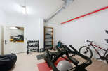 This home gym boasts an array of equipment, including weights, kettlebells, a rowing machine, and an exercise bike, perfect for a comprehensive workout.