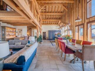This stunning chalet boasts a spacious open-plan living area with exposed wooden beams and a cozy fireplace, perfect for relaxing after a day on the slopes.