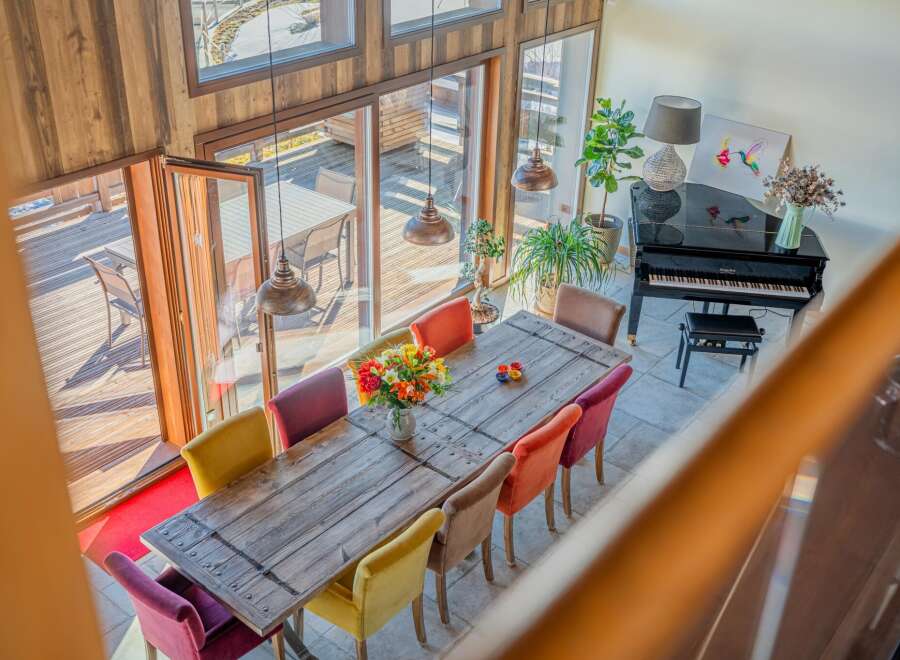 This stunning home boasts a spacious dining area with a rustic wooden table and colorful chairs, perfect for entertaining guests.