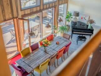 This stunning home boasts a spacious dining area with a rustic wooden table and colorful chairs, perfect for entertaining guests.