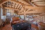 This stunning chalet boasts a breathtaking open-plan living area with exposed wooden beams and a cozy leather sofa.