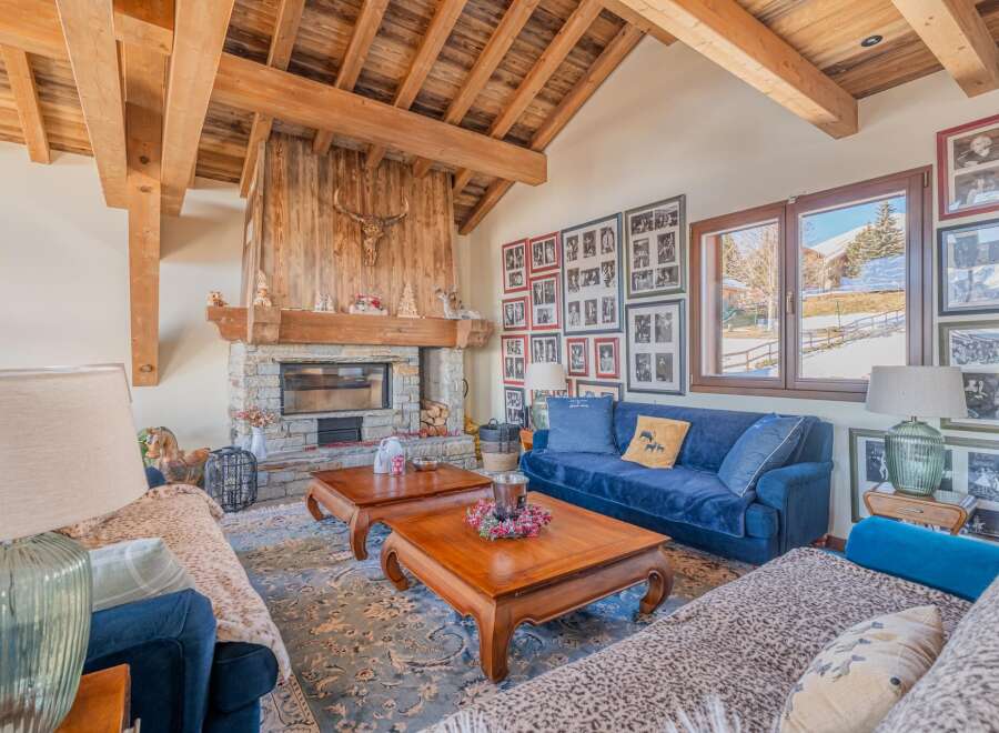 This stunning chalet boasts a spacious living area with exposed wooden beams, a cozy fireplace, and large windows offering breathtaking mountain views.