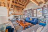 This stunning chalet boasts a spacious living area with exposed wooden beams, a cozy fireplace, and large windows offering breathtaking mountain views.
