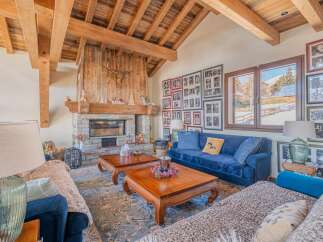 This stunning chalet boasts a spacious living area with exposed wooden beams, a cozy fireplace, and large windows offering breathtaking mountain views.