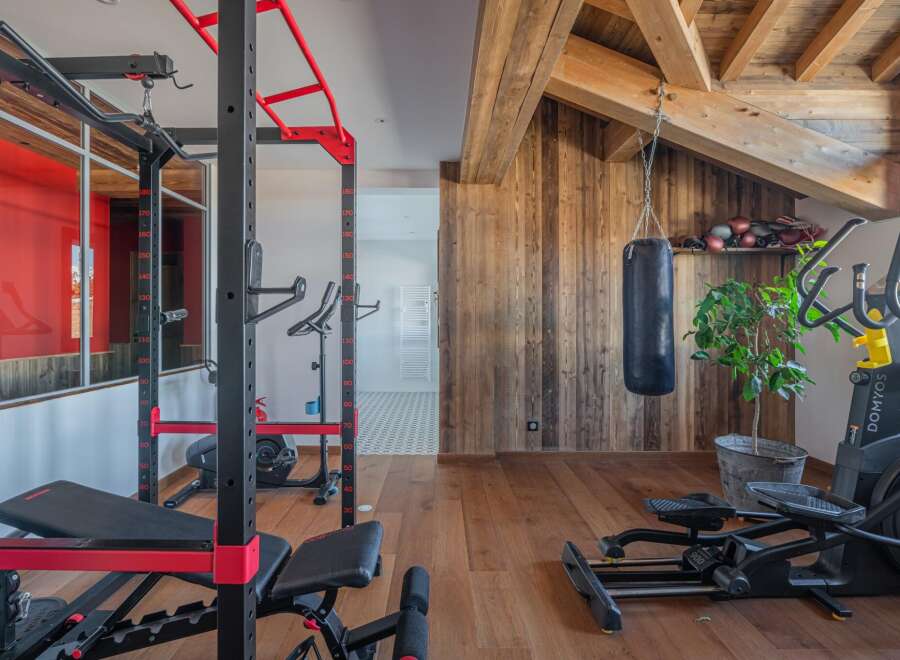 This stunning home gym boasts a full set of professional-grade equipment, including a squat rack, weight bench, and elliptical machine.