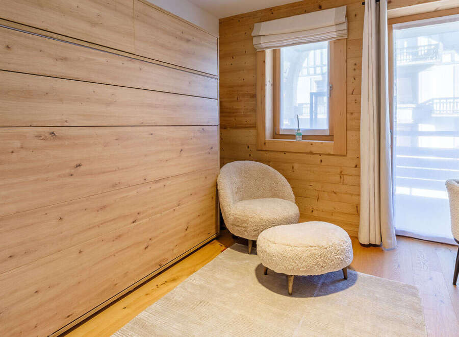 This cozy bedroom features a stunning wooden wall and a comfortable seating area.