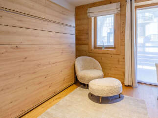 This cozy bedroom features a stunning wooden wall and a comfortable seating area.