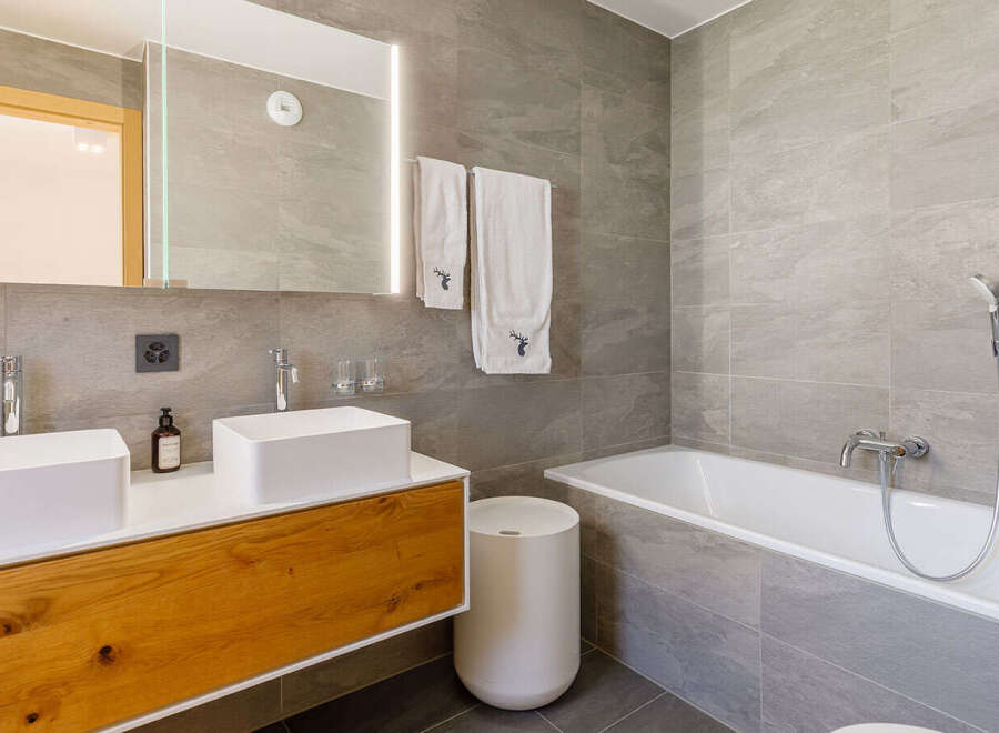 This modern bathroom features a sleek design with a double vanity and a luxurious bathtub.