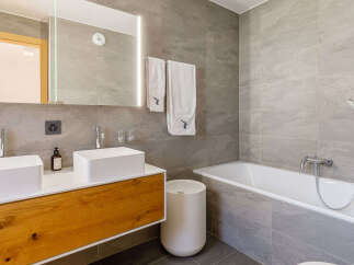 This modern bathroom features a sleek design with a double vanity and a luxurious bathtub.