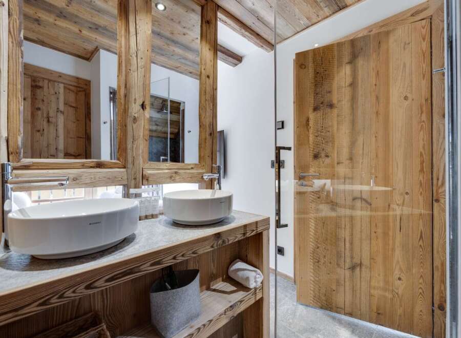 This luxurious bathroom boasts a stunning double vanity with sleek, modern sinks and rustic wooden cabinetry.