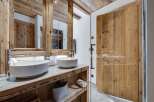 This luxurious bathroom boasts a stunning double vanity with sleek, modern sinks and rustic wooden cabinetry.