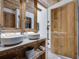 This luxurious bathroom boasts a stunning double vanity with sleek, modern sinks and rustic wooden cabinetry.